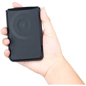 A black magnetic card wallet and wireless charging stand held in a hand. It features a logo on the surface.