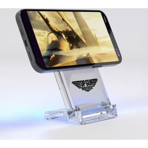 A clear acrylic wireless charging stand holding a smartphone, featuring a logo at its base. The stand has a sleek design.