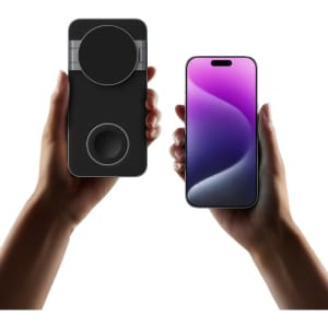 A black magnetic wireless charging station held in one hand, with a smartphone in the other hand displaying a gradient screen.