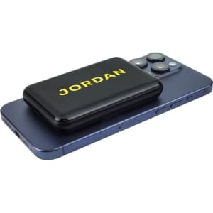 A black power bank with yellow branding, placed on a blue smartphone, showcasing its compact design.
