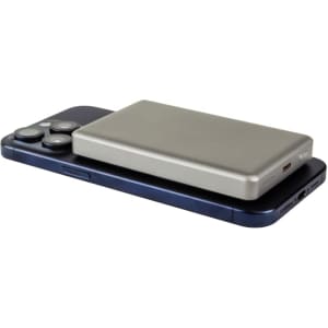 A silver MagSafe wireless power bank rests on a dark phone. The power bank has charging ports and a brand logo.