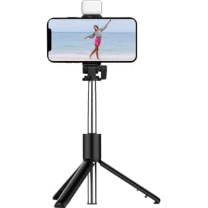A black LED selfie stand with a smartphone mounted, featuring a light on top and adjustable tripod legs.