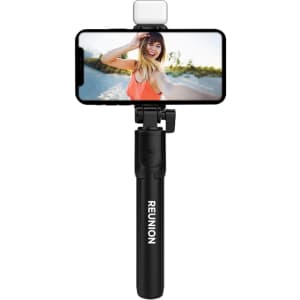 A black selfie stand with an attached phone and LED light, featuring the word "REUNION" on the handle.