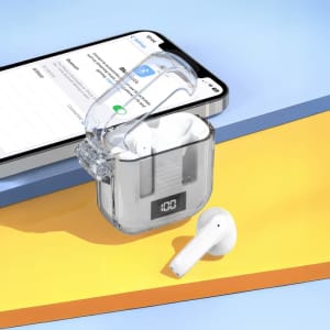A pair of white Riverton Crystal TWS Earbuds in a transparent charging case, positioned next to a smartphone on a colourful surface.