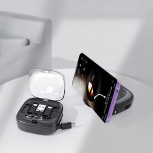A black retractable cable set in a case, with a smartphone propped up, displaying a music player interface.