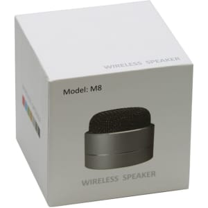 A compact black wireless speaker in a white box featuring a branded logo and model number.