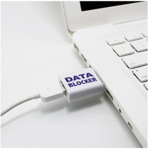 A USB data blocker in grey connected to a laptop, preventing data transfer while allowing charging.