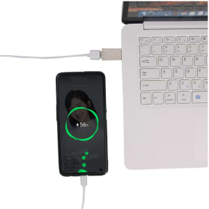 A USB data blocker in wheat straw material connects a smartphone to a laptop, displaying a charging indicator.