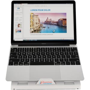 A grey foldable laptop stand supporting a laptop displaying a presentation with scenic images. The stand has a logo.