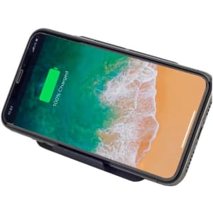 A black wireless charger stand with a phone displaying a fully charged battery on a beach-themed background.