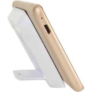 A gold phone is resting on a white wireless charger stand, angled for optimal charging. The stand includes a logo.