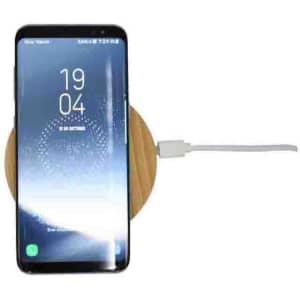 A wireless fast charger with a bamboo base, featuring a smartphone positioned on top.