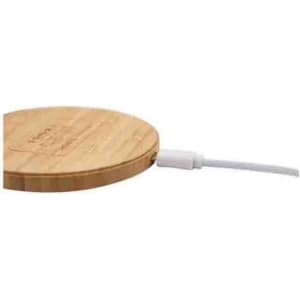 A bamboo wireless charger in a circular shape with a white charging cable attached.
