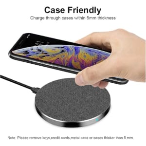 A round, grey tweed wireless charger with a smartphone on top, featuring a subtle branding logo.