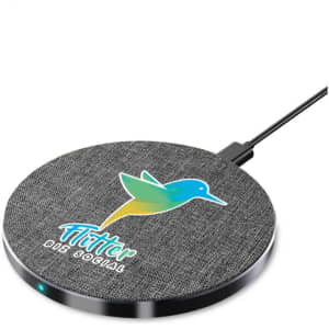 A round wireless charger in grey with a fabric texture, featuring a logo and a charging indicator light.