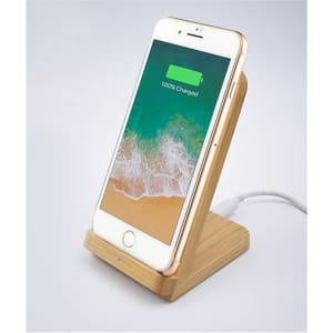 A bamboo wireless charger in natural tones with a smartphone displaying a fully charged battery. Features a logo.