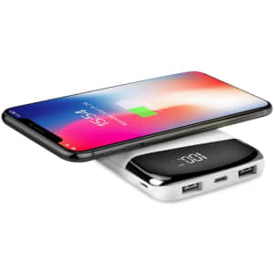 A wireless power bank in white with two USB ports, charging a smartphone. The smartphone displays a battery charging indicator.
