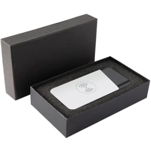 A grey and white wireless power bank in a black box with foam padding. It has a logo on the surface.