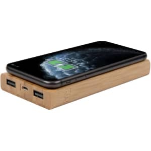 A bamboo wireless power bank in natural wood finish, featuring two USB ports and a smartphone on top.