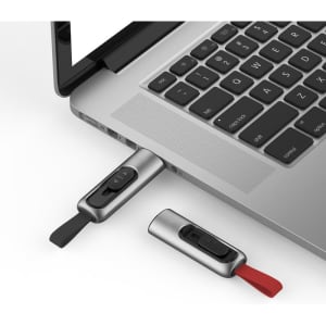 A silver and black Churchill flash drive is plugged into a laptop, with a red one next to it.