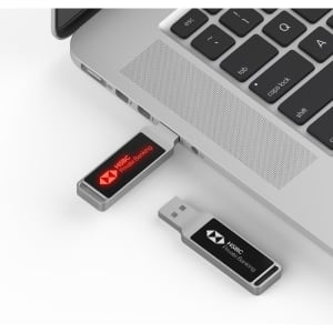 A black and silver LED flash drive connected to a laptop, featuring a logo on the drive.
