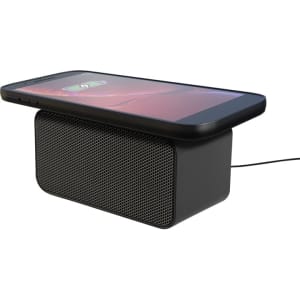 A black wireless charging speaker with a phone placed on top, featuring a mesh speaker grille and a charging cable.