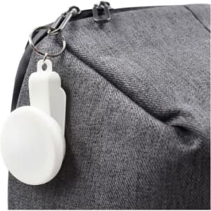 A grey bag with a white keyring attachment prominently displayed on the zipper.