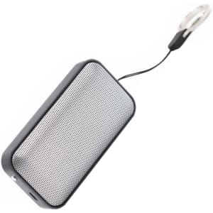 A compact black wireless speaker with a mesh front and a loop for attachment. It features a logo on the side.