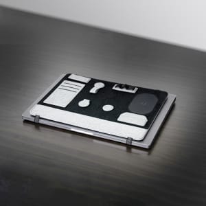 A grey and black laptop organiser featuring various compartments and a logo, resting on a dark surface.