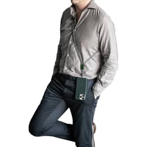 A green crossbody phone strap attached to a phone, worn by a person in a light grey shirt and dark trousers.