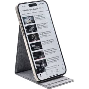 A smartphone on a grey wireless charger stand, displaying a video streaming interface. The stand has a sleek design.