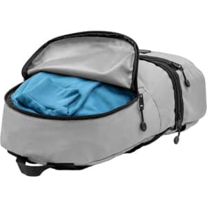 A grey bum bag with a partially open zipper revealing a blue shirt inside. It has a logo on the exterior.