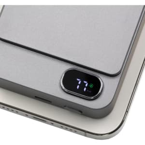 A grey magnetic wireless power bank with a digital battery indicator, resting on a phone.