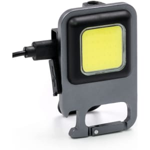 A grey LED multi-tool with a square light panel and a clip for attachment. Features a charging port on the side.
