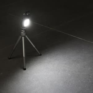 A multi-tool featuring a COB LED light on a small tripod, with a sleek design in black and silver.