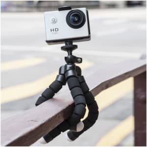 A flexible black tripod with a small white camera attached, resting on a wooden railing.