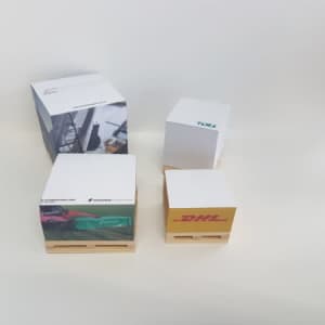 A set of cube notepads in various sizes, featuring colourful designs and logos, displayed on small wooden pallets.