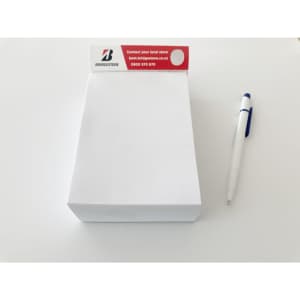 A white notepad with a branded top and blue pen beside it, designed for office use.