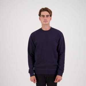 A navy blue jumper with a crew neckline, featuring a logo on the front. The model stands against a plain background.