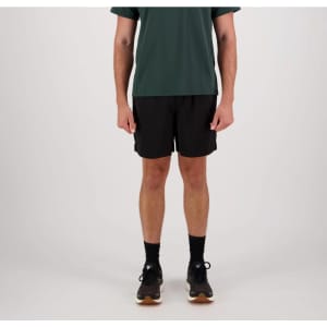 Black sports shorts displayed on a model wearing a green top, with black socks and shoes, featuring a logo.