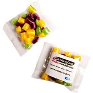 A sealed packet of assorted humbugs in vibrant green, yellow, and purple colours, with a logo and branding visible.