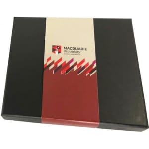 A black gift box featuring a red and white label with a logo, containing assorted chocolates or truffles.