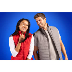 A red and grey eco puffer vest worn by a man and a woman, both smiling against a blue background.