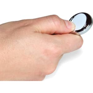A hand holds a shiny, silver ball marker designed for use in golf.