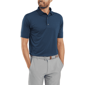 A men's navy polo shirt with a collar and short sleeves, paired with light grey trousers. The model has a branded belt.