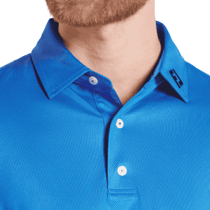 A close-up of a men's blue polo shirt featuring a tonal dot print and a logo on the collar.