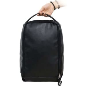 A black PU leather shoe bag held by a hand, featuring a zip closure and a handle for easy carrying.