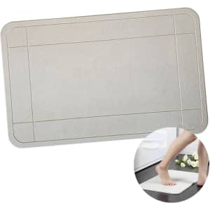A textured rectangular bath mat in a light grey colour with a bordered design and a circular inset of a foot stepping on it.