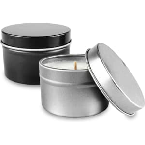 A silver and a black tin candle with lids, featuring a lit wick inside the silver tin.