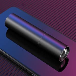 A sleek black torch lying on a reflective surface, showcasing its cylindrical design and shiny finish.